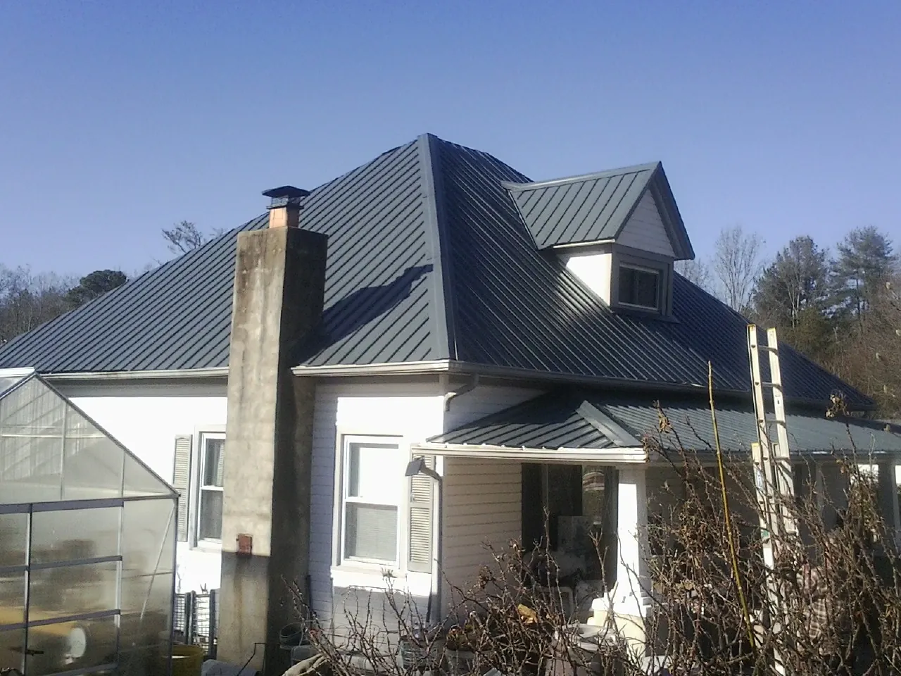 Dark blue standing seam metal roof on a white farmhouse with dormer — Slate & Tile Roof Repair by Roofing Brothers in Dickson