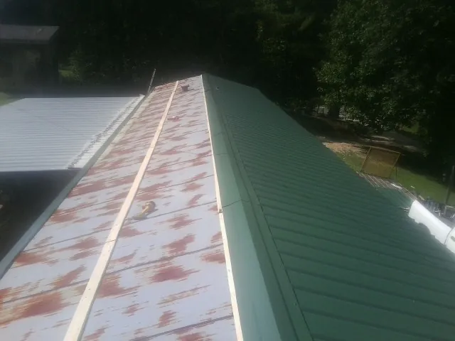 Old rusted panels beside newly installed green metal roofing — Wind Damage Roof Repair by Roofing Brothers in Dickson