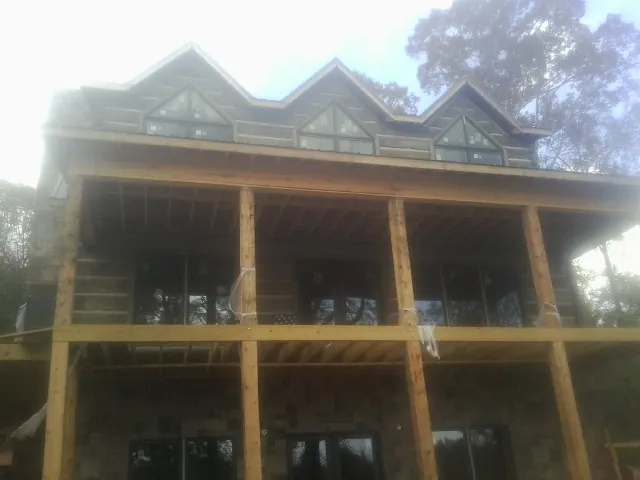 Dormers and porch framing on a large log home under construction — Roof Coating work by our crew in Dickson