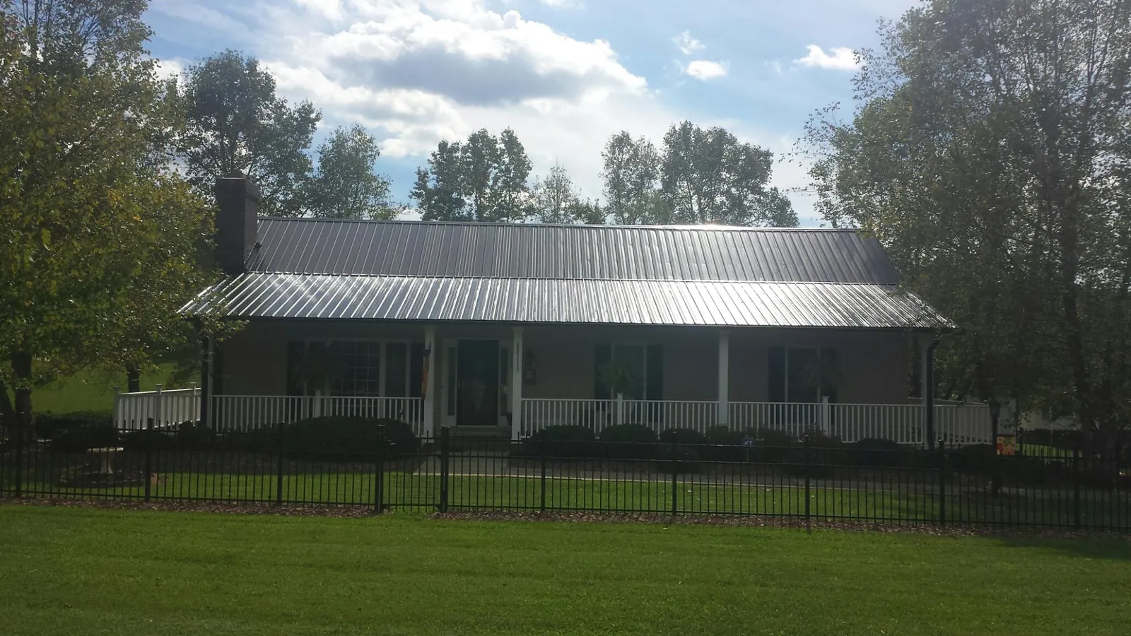 Gray metal roof on a brick ranch with a full width front porch — Gutter Guard Installation work by our crew in Dickson