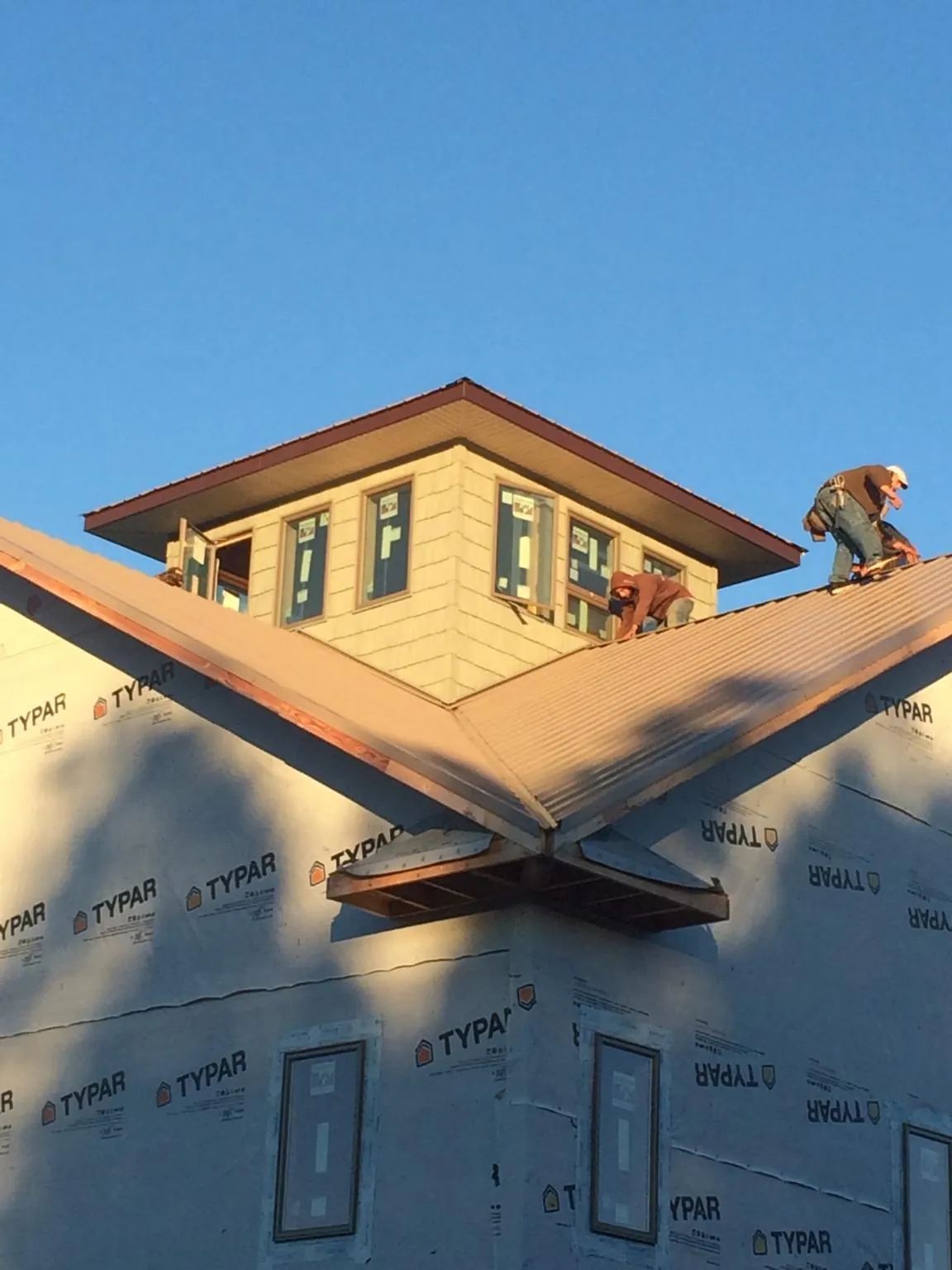 Roofers working around a rooftop cupola on a new metal roof at sunset — Roof Waterproofing in Dickson by Roofing Brothers